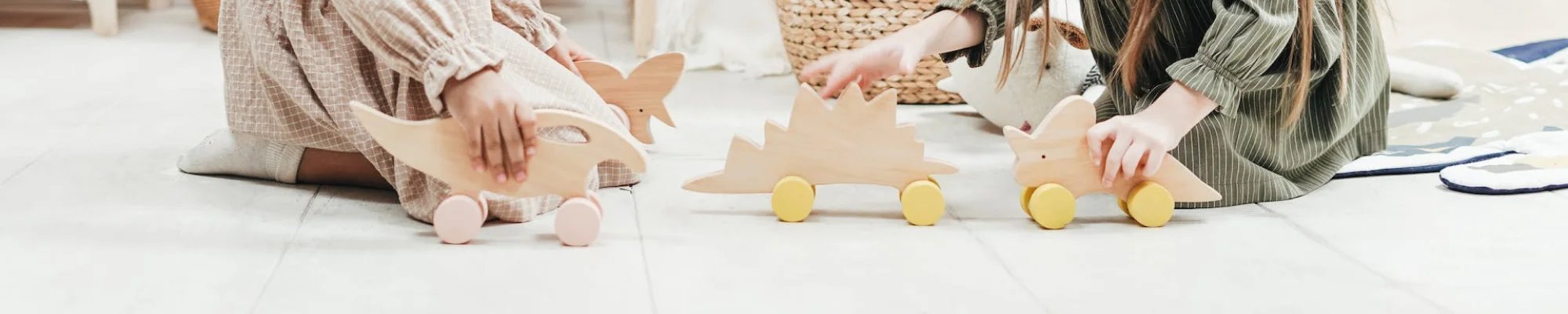 girls sitting on wood floors, playing with animal toys